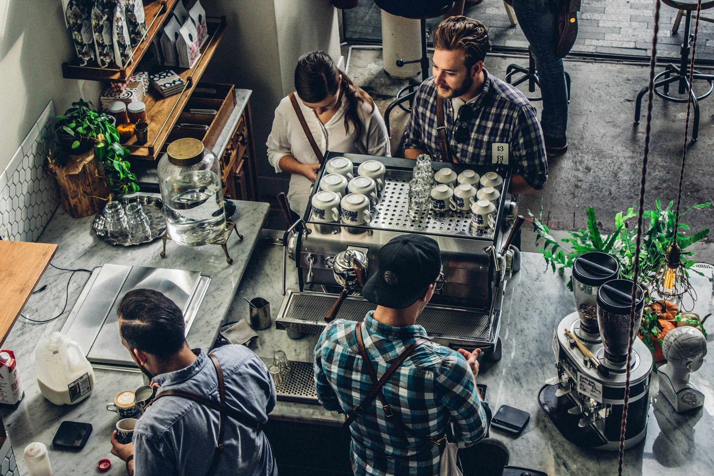 Owner serving customers at the counter of a busy independent coffee shop, the kind of small business Hampala helps with AI and automation
